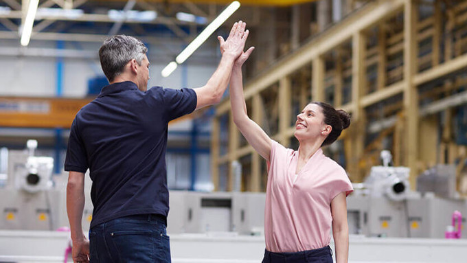 Coperion Mitarbeiter geben sich High-Five in Montagehalle