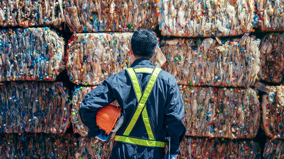 worker in front of piles of plastic waste